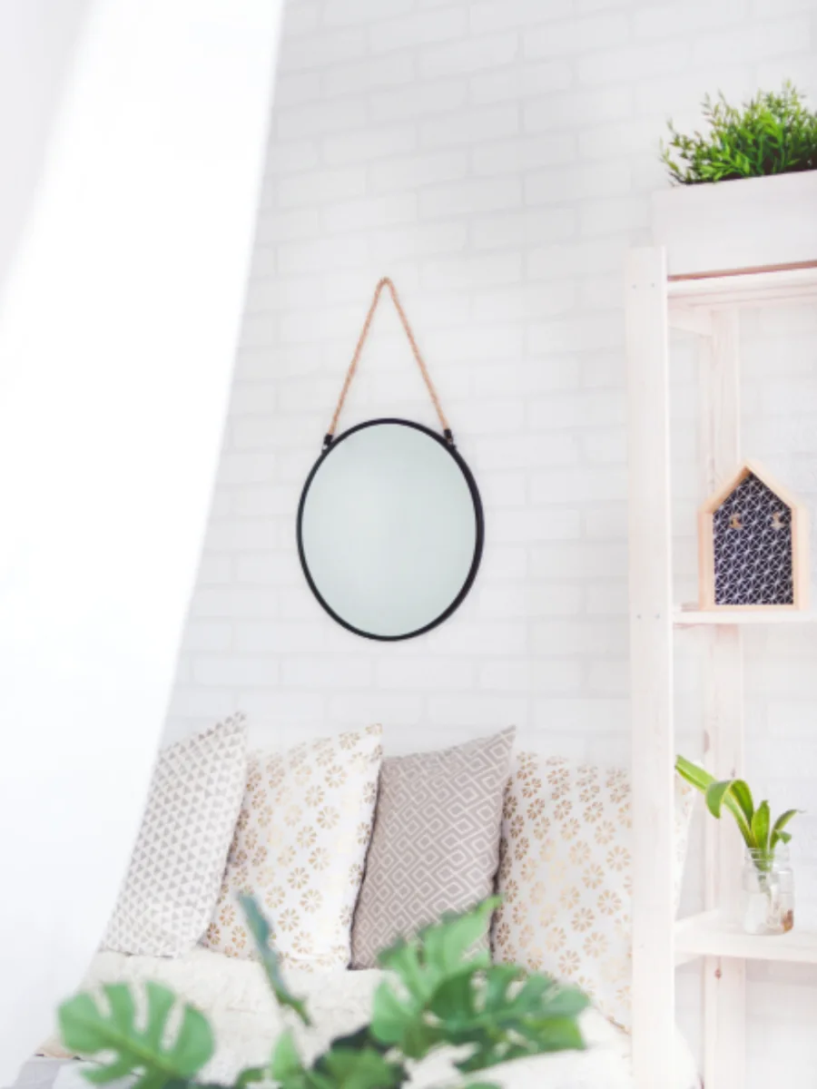 Round wall mirror above a seating corner with cushions and plants. Illustrative photograph, not a before-and-after test. Studio 7042 / StockSnap, CC0.