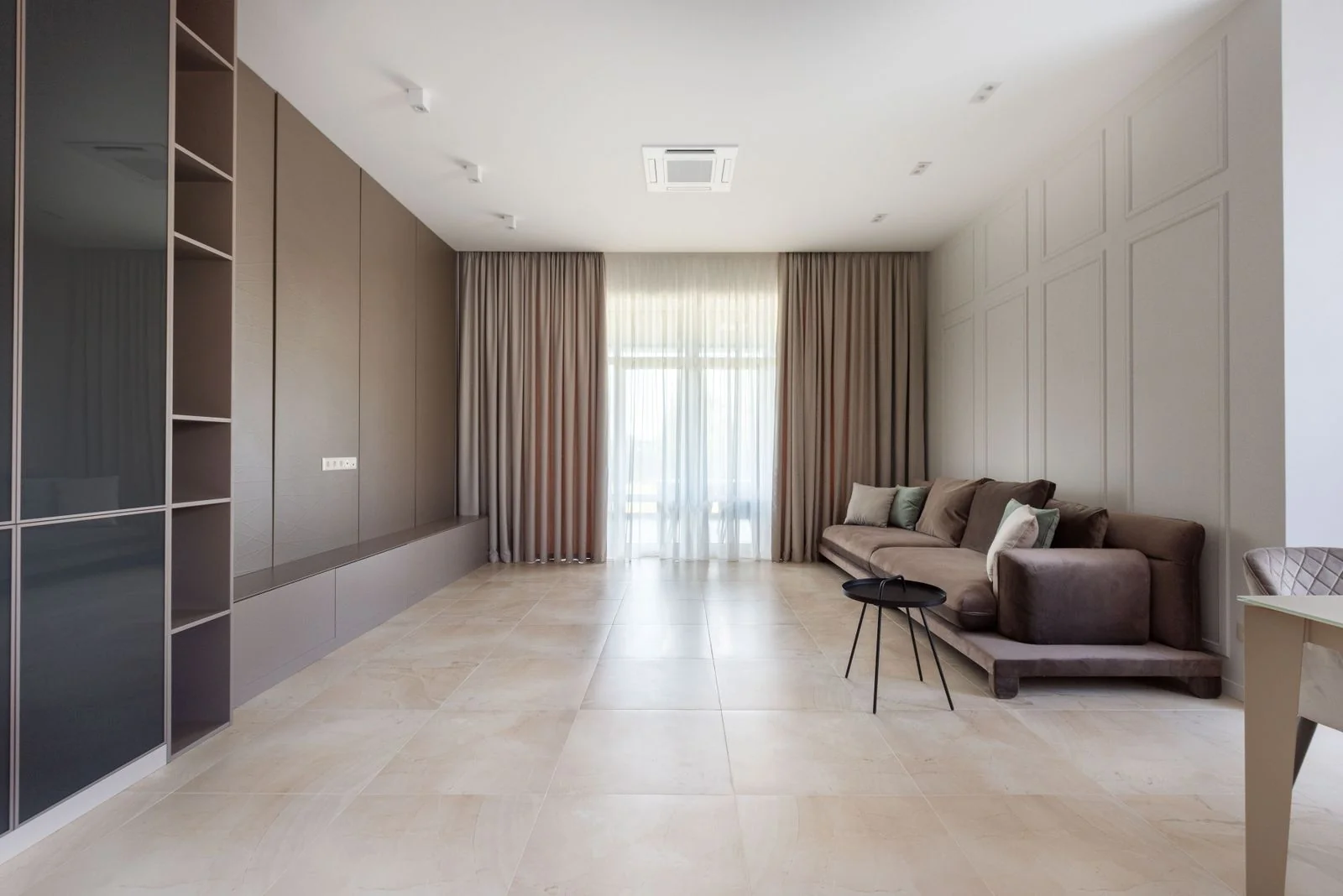 A living room with full-height curtains and a lighter central curtain layer