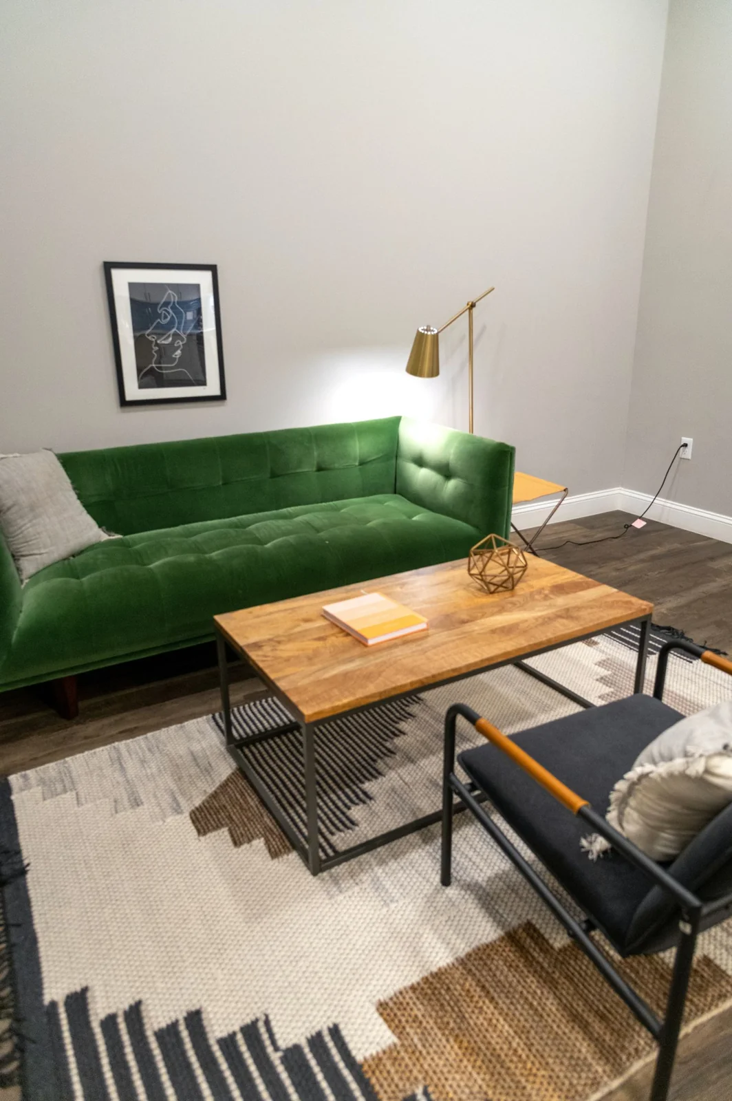 A patterned rug under a wooden coffee table beside a green sofa