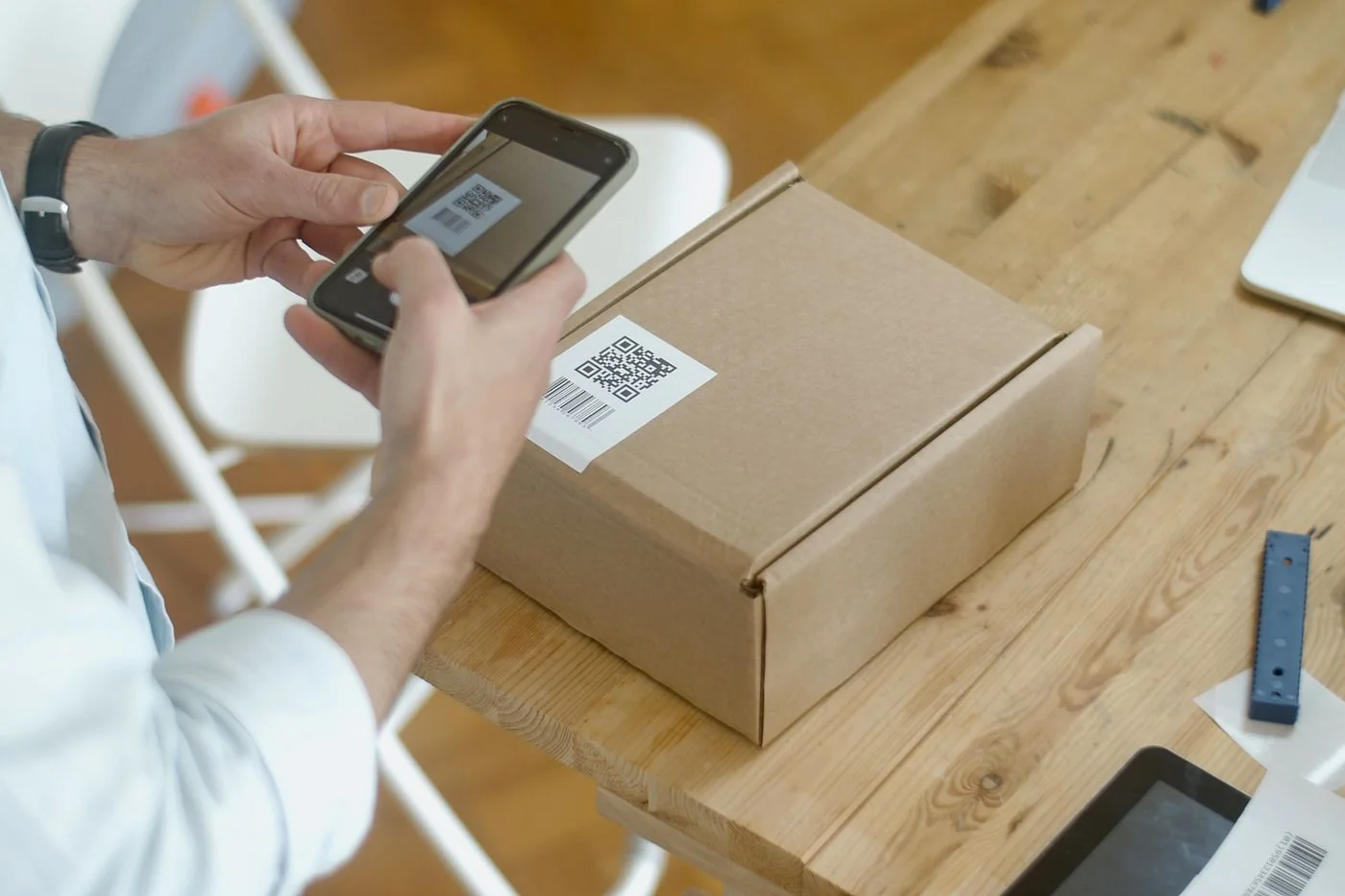 Smartphone scanning a QR code on a parcel. Illustrative use, not documentation of a scam. Kampus Production / Pexels, Pexels License.